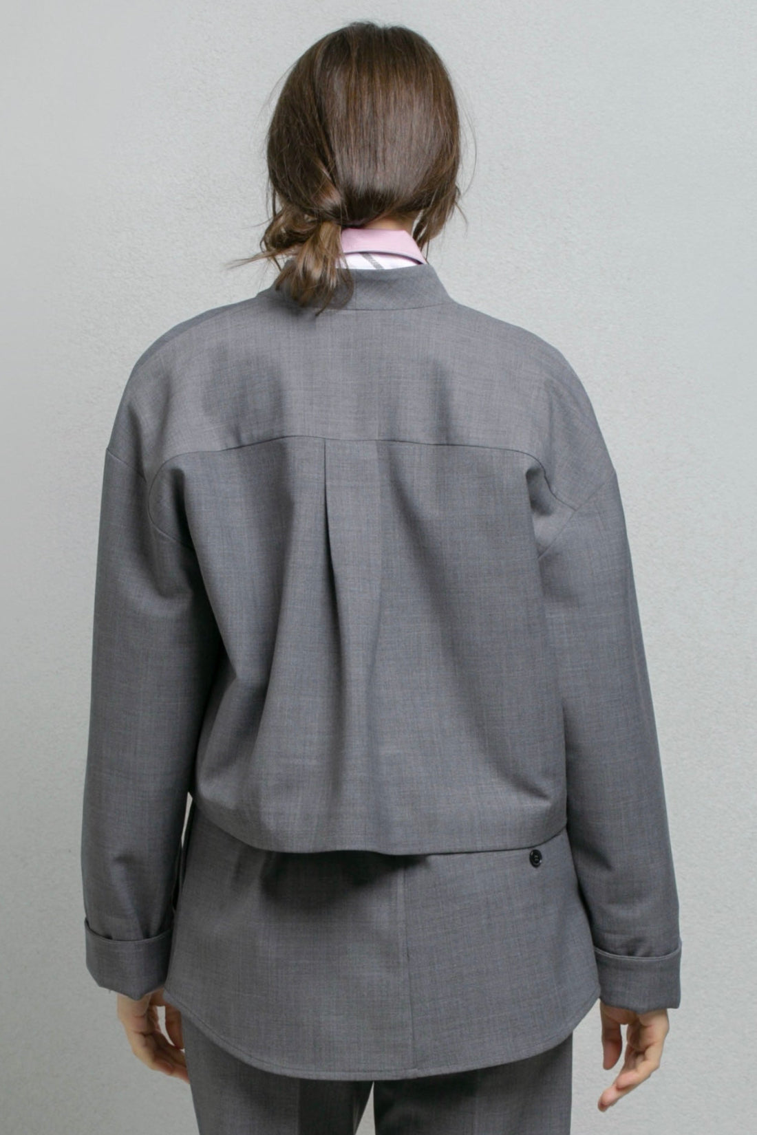A model wearing a gray two-piece suit consisting of a cropped long-sleeve jacket and matching trousers,